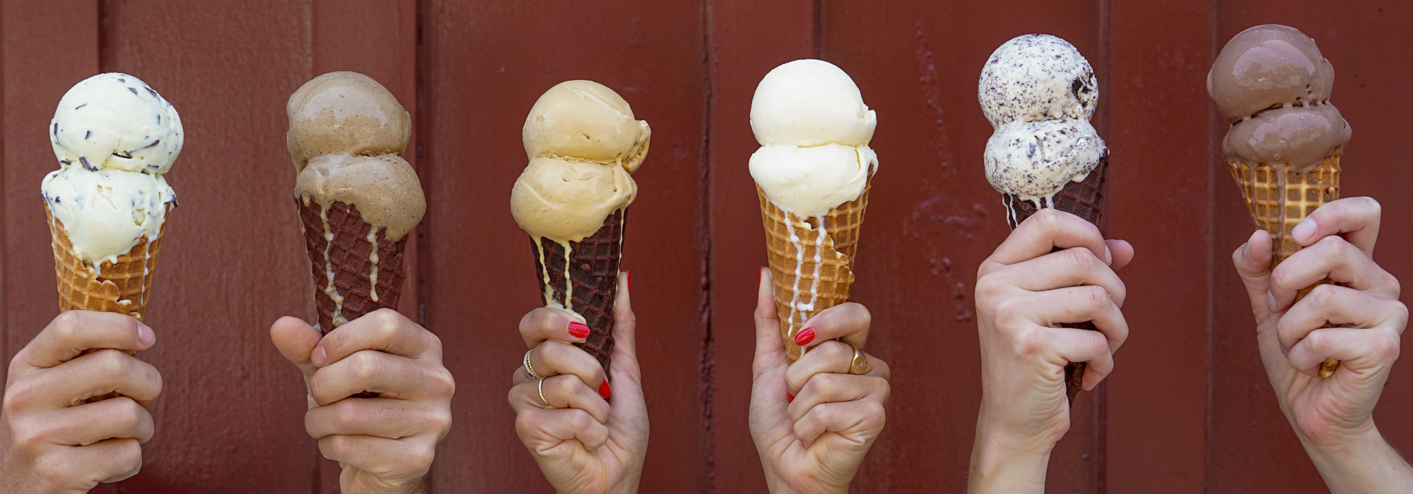 Hands holding a variety of ice cream cones