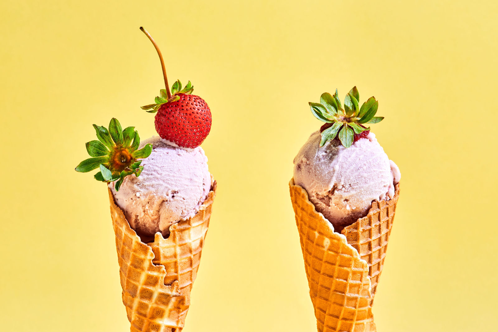 Strawberry Ice Cream two vanilla cones holding strawberry ice cream topped with fresh strawberries